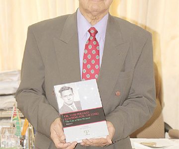 Yesu Persaud with the first volume of his autobiography at the book launch earlier this year (Stabroek News file photo)
