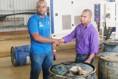 A Ministry of Natural Resources and Environment official (left) hands over four drums of fuel to PGC chairman Shawn James. (GINA photo)
