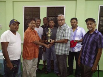 Manniram Shew (second left) of Shew’s General Store, hands over the winning trophy to Looknauth “King” Persaud in the presence of other teammates. 