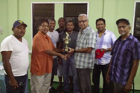 Manniram Shew (second left) of Shew’s General Store, hands over the winning trophy to Looknauth “King” Persaud in the presence of other teammates.