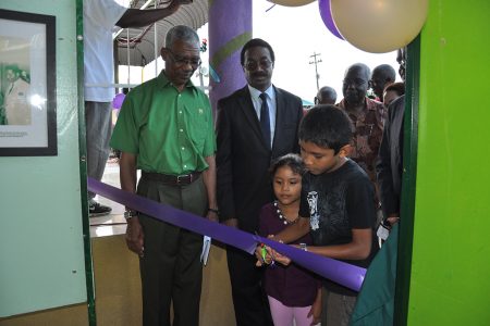 PNCR Leader David Granger (left) watches on approvingly as the ribbon declaring the institute open is cut. (PNCR photo)