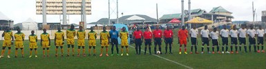 The starting 11 of the Golden Jaguars (left) lining up before the start of their CFU Cup Qualification tourney opener against Dominica. (Picture courtesy of vibesantigua.com).  