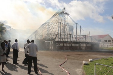 Officials watch as fire razed the Umana Yana today. 