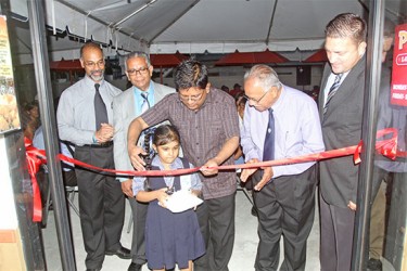 Finance Minister Dr Ashni Singh cuts the ribbon during the commissioning of the second Popeye’s Louisiana Kitchen opening on Camp Street yesterday. 