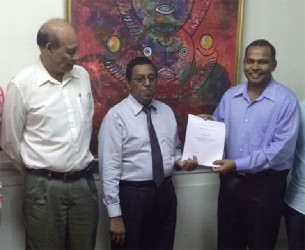 Legal Advisor of the Guyana Horse Racing Authority (GHRA), Rajendra Poonai (centre), handing over the draft legislation to Minister Dr. Frank Anthony in the presence of GHRA’s president Vic Oditt.