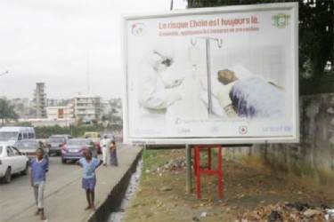 People walk past a billboard displaying a government message about Ebola, which reads: “The risk of Ebola is still there. Let us apply the protective measures together”, on a street in the Ivory Coast capital Abidjan September 10, 2014. REUTERS/ Luc Gnago 