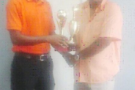 Chief Executive Officer (CEO) of the Berbice Bridge Company Incorporated (BBCI) Omadatt Samaroo hands over the trophies to Johnny Marcus of the Guyana Draughts Association.