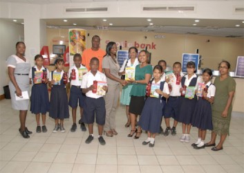 Scotiabank’s Jennifer Cipriani (centre, right) presents a collection of books to the teachers and students of one of the recipient schools of its Bright Futures partnership with the Guyana Book Foundation.  
