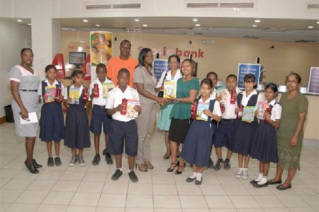 Scotiabank’s Jennifer Cipriani (centre, right) presents a collection of books to the teachers and students of one of the recipient schools of its Bright Futures partnership with the Guyana Book Foundation.

