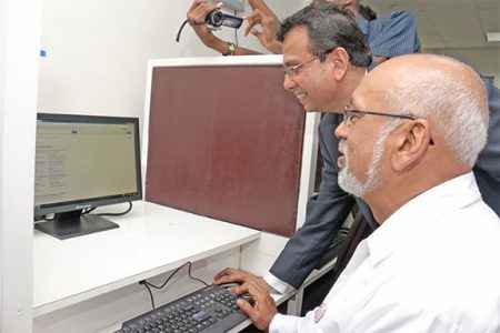 President Donald Ramotar (sitting) and CEO of GT&T R.K. Sharma do some browsing in the re-commissioned computer lab up UG