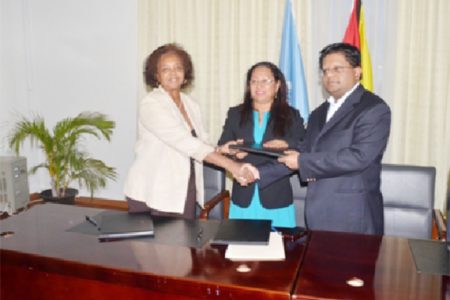United Nations Development Programme (UNDP) Resident Representative and UN Coordinator Khadija Musa and Minister of Finance Dr. Ashni Singh shake hands after signing the $1.3B agreement, while Minister of Amerindian Affairs Pauline Sukhai looks on. (Government Information Agency photo)