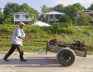 A man pushing a boat engine in a two wheeled cart 