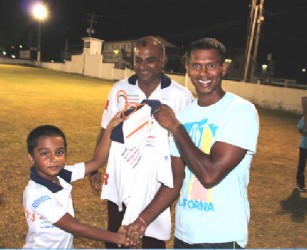 Newest Floodlights Softball Cricket Club member Shivnarine Chanderpaul receives his team shirt from the youngest Floodlights player eight year old Romeo Deonarine.