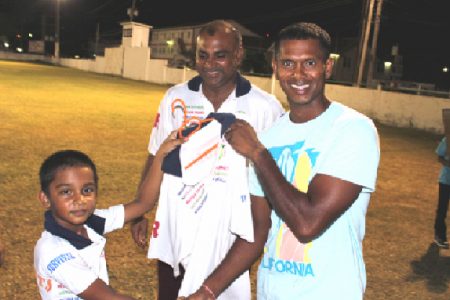 Newest Floodlights Softball Cricket Club member Shivnarine Chanderpaul receives his team shirt from the youngest Floodlights player eight year old Romeo Deonarine.