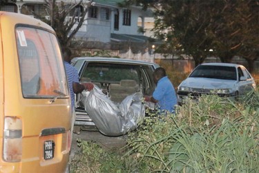 The badly decomposed body being removed by undertakers on Monday evening. 