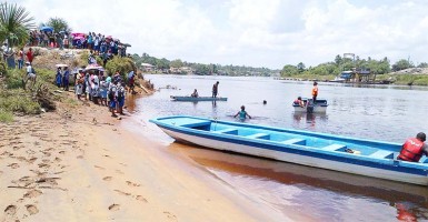 Boats and divers searching the Demerara River for Omar Mitchell yesterday while relatives and others look on. (Photo by Jeff Trotman)