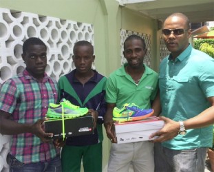 Cleveland Thomas (2nd right) and Matthew McKenzie (2nd left) received athletic gear and supplements yesterday from Kwame Ridley (left) and Carey Griffith.  