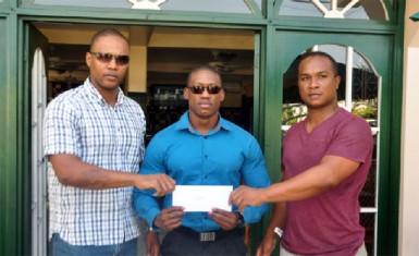 Carey Griffith (left) and Noel Lancaster (right) presenting monetary sponsorship to Mr. Guyana Kerwin Clarke yesterday. (Orlando Charles photo) 