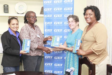  Dr. Joyce Jonas (second, right) hands over a copy of the Study Guide to Assistant Chief Education Officer Leslyn Edwards-Charles (second, left). They are flanked by GT&T Public Relations Officers Nadia DeAbreu (left) and Allison Parker (right). (Photo by Arian Browne)