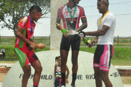 The top three cyclists of yesterday’s event celebrating with champagne on the podium. (Orlando Charles photo)
