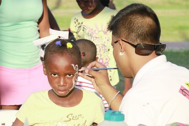 A young girl is treated to a professional face-paint job by a Bravo Arts artist on Saturday at the Child Protection Week Fun Day. (Photo by Arian Browne) 