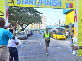 Cleveland Thomas stops his watch outside Courts’ Main Street office after recording the fastest 10km for the year on Sunday. (Orlando Charles photo)