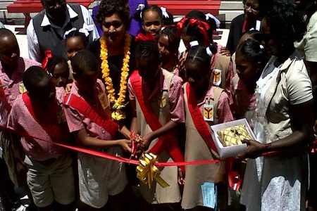 Pupils of St Agnes Primary cut the ribbon at the commissioning of their school yesterday while  Education Minister Priya Manickchand, school and ministry officials look on.
