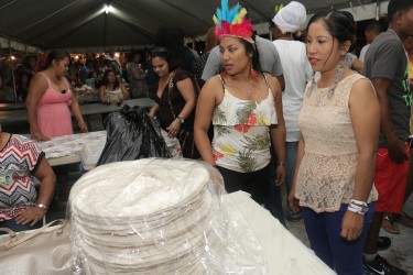 Patrons admiring a huge stack of cassava bread at the opening of the Amerindian Village and Amerindian Heritage Month at the Sophia Exhibition Site yesterday.  (Photo by Arian Browne)