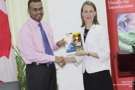 Minister of Natural Resources and the Environment Robert Persaud receives the relaunched Guyana Mining Information Toolkit from Canadian High Commissioner Nicole Giles. 