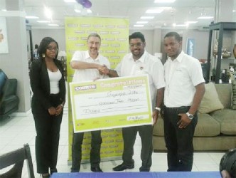 Minister of Tourism, Industry and Commerce, Irfaan Ali (second from right) receives the cheque for $2 million from Courts Country Manager Clyde de Hass (second from left) in the presence of Roberta Ferguson, Public Relations Officer (extreme left)  and Pernell Cummings,  Marketing Manager.    