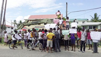 Residents of Plaisance hold signs in front of the Plaisance/Industry Neighbourhood Democratic Council (NDC) picketing what they charge is a land grab by the government through the Interim Management Committee and the newly appointed overseer.  