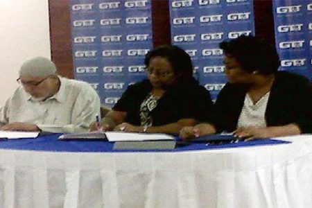 From left: President of CIOG Fazeel Ferouz and Marketing Manager of GT&T Fay Wharton signing the agreement while Public Relations Officer of GT&T Allison Parker looks on.
