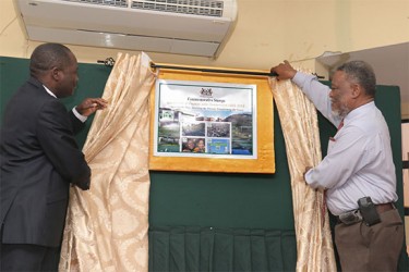 Vice Chancellor of the University of Guyana Jacob Opadeyi (left) and Prime Minister Sam Hinds unveil a plaque featuring the new collection of commemorative stamps launched yesterday in observance of UG’s 50th anniversary. (See story on page 17) (Arian Browne photo) 