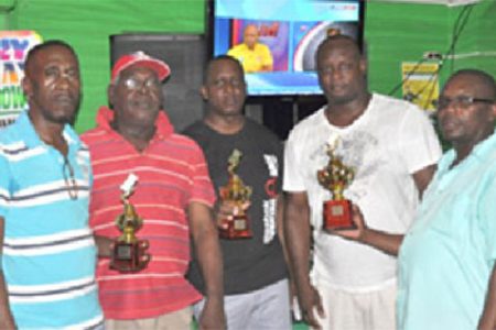 Some members of Strikers Sports Club display the trophies. Neville `Cody’ Cadogan is at right.