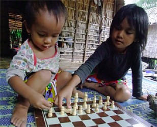 Fixing the Knight: The white pieces are in place, except the Knight, as the photo demonstrates. The picture was taken in Cambodia where students of a select school in a remote province are learning the Western form of chess, thanks to French former child chess star, Karelle Bolon. Bolon has adopted a simple and effective way of training children to play chess – you train the schoolteacher, and the teacher will in turn teach the young ones. 