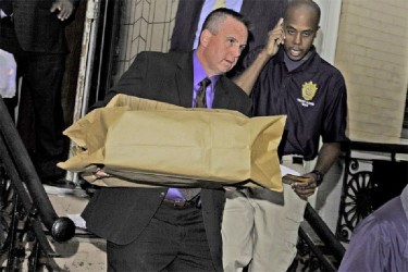 A New York Police Department official carries evidence out of a home in Brooklyn on Thursday. (New York Post photo)