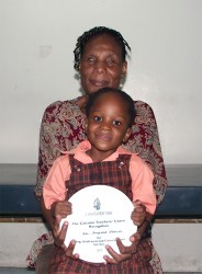 Ingrid Peters and her granddaughter Akia Peters holding the plaque which was presented to her by the Guyana Teachers Union at this year’s observance of World Teachers Day. 