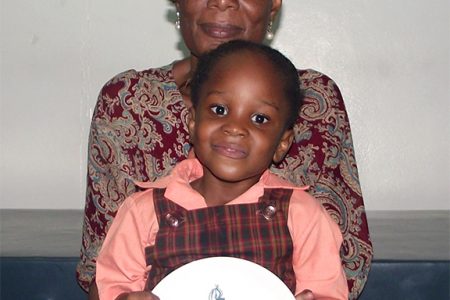 Ingrid Peters and her granddaughter Akia Peters holding the plaque which was presented to her by the Guyana Teachers Union at this year’s observance of World Teachers Day.
