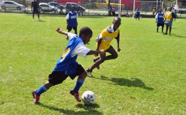 Tucville Primary’s Rayheem Marques (left) trying to evade his St. Gabriel Primary marker during his side’s 3-0 win  