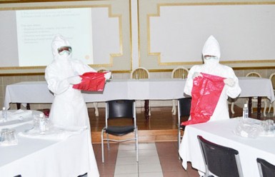 Two participants yesterday demonstrating the correct usage of protective gear during one of the presentations on the Ebola virus. (GINA photo) 