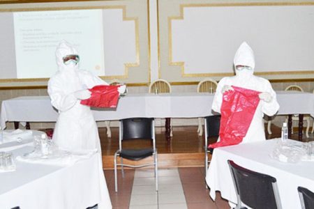 Two participants yesterday demonstrating the correct usage of protective gear during one of the presentations on the Ebola virus. (GINA photo)
