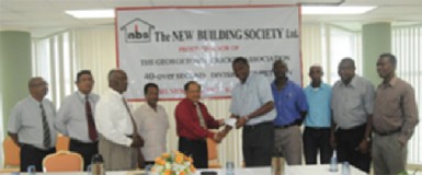 Chief Executive Officer of the New Building Society Ahmad Khan (left) presents the sponsorship cheque to President of the GCA Roger Harper in the presence of other officials of NBS and GCA. 