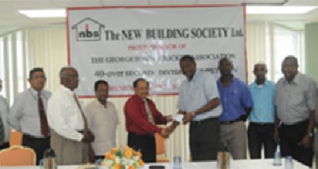 Chief Executive Officer of the New Building Society Ahmad Khan (left) presents the sponsorship cheque to President of the GCA Roger Harper in the presence of other officials of NBS and GCA.
