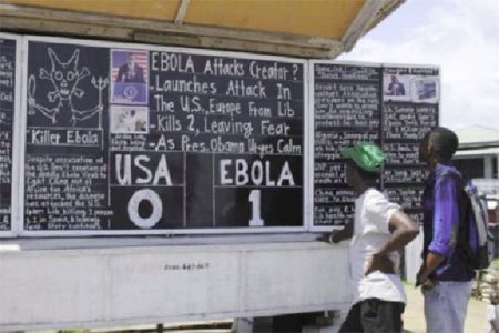 Bystanders read headlines saying ‘Ebola 1: USA 0’ at the Daily Talk, a street side chalkboard newspaper, in Monrovia October 16, 2014. (Reuters photo)
