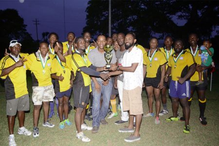 The victorious Yamaha Caribs outfit pose with the winner’s trophy of the Windjammer/Golden Brook/Toney Sevens League yesterday at the National Park.