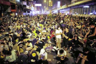 Pro-democracy protesters sit on a street as they block an area of the Mongkok shopping district of Hong Kong October 20, 2014.  REUTERS/Carlos Barria 