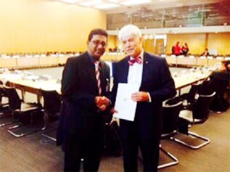 Minister of Legal Affairs and Attorney General, Anil Nandlall (left) hands over the letter of commitment from President Donald Ramotar to President of the Financial Action Task Force, Roger Wilkins AO in Paris. (GINA photo)