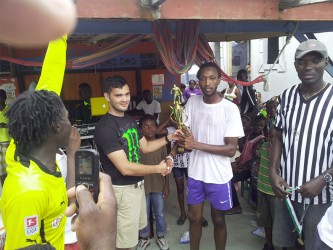 Albouystown-A captain Jermin Daniels (second, right) collecting the winner’s trophy from Stag Brand manager John Maikoo during the brief presentation ceremony.