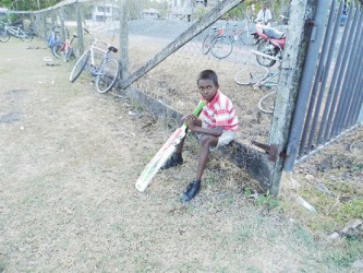 Young boy waiting patiently for his turn to bat during cricket practice at the ball field 