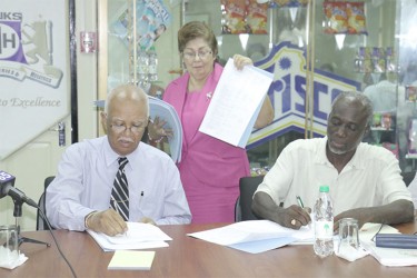 Banks DIH Chairman, Clifford Reis (left) and General President of the General Workers Union, Norris Witter signing the agreement as Techla Gonsalves looks on. 